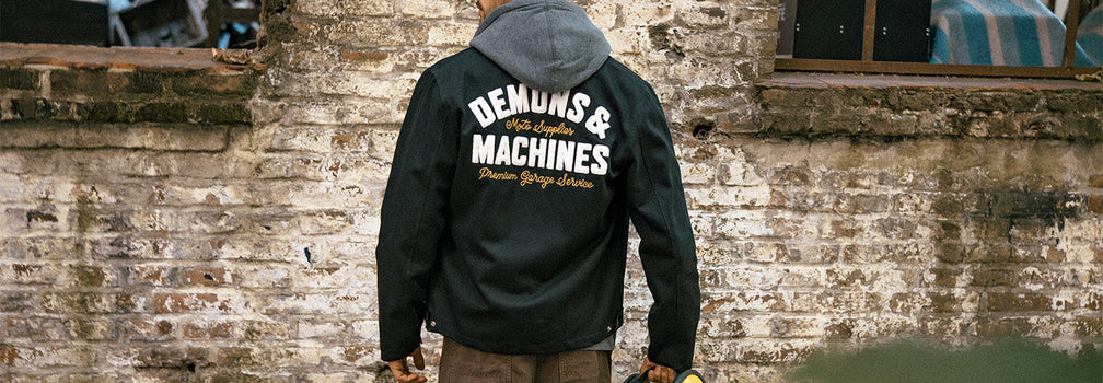 Hombre de espaldas con campera Demons & Machines en entorno urbano estilo workwear