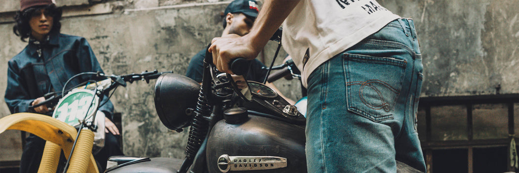 MODELOS JUNTO A MOTO HARLEY-DAVIDSON EN ESCENA URBANA, LOOK CASUAL DENIM Y WORKWEAR