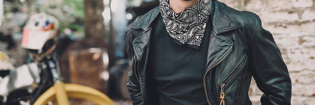 CAMPERA BIKER DE CUERO NEGRO CON PAÑUELO BANDANA Y ESTÉTICA ROCKER JUNTO A MOTO