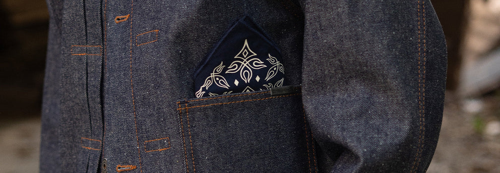 Detalle de bolsillo en prenda de denim con costuras visibles y bandana en look workwear de Demons & Machines