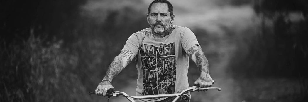 FOTOGRÁFO PABLO FRANCO SOBRE MOTO EN BLANCO Y NEGRO CON REMERA GRÁFICA DEMONS & MACHINES Y ACTITUD CRUDA