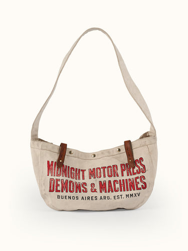Inspirado en las primeras bolsas usadas para el reparto de periódicos, nuestro Bolso Newspaper puede usarse sobre el hombro o cruzado. Confeccionado artesanalmente en lona pesada de algodón, con broches snap metálicos, presillas en cuero vacuno con tratamiento envejecido y correa ancha de algodón reforzada con múltiples pespuntes. Cuenta con bolsillo interno. Arte de marca de estética vintage estampado en serigrafía.