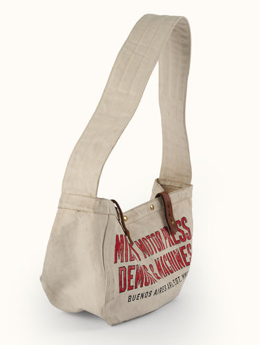 Inspirado en las primeras bolsas usadas para el reparto de periódicos, nuestro Bolso Newspaper puede usarse sobre el hombro o cruzado. Confeccionado artesanalmente en lona pesada de algodón, con broches snap metálicos, presillas en cuero vacuno con tratamiento envejecido y correa ancha de algodón reforzada con múltiples pespuntes. Cuenta con bolsillo interno. Arte de marca de estética vintage estampado en serigrafía.