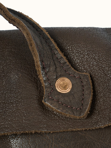 Primer plano del anclaje de la manija con remache de cobre sobre el cuero arrugado del Bolso Messenger #color_marron
