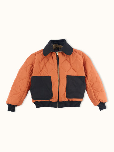 Campera Demons & Machines reversible estilo aviadora. Este estilo remite al modelo de camperas ALPHA, icónicas de la Fuerza Aérea por su diseño funcional para pilotos, caracterizadas por materiales resistentes, puños tejidos, bolsillos utilitarios y reversibilidad naranja para visibilidad en emergencias.