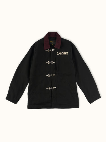 Campera confeccionada en canvas pesado de algodón, con cuello en corderoy a contratono. Acceso frontal con cierre de metal oculto y mosquetones de metal a la vista. Este detalle está inspirado en los uniformes de los bomberos, sirven principalmente para cerrar de forma segura y rápida las prendas, garantizando que no se abran durante la emergencia, además de resistir altas temperaturas. #color_negro