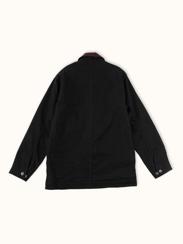 Campera confeccionada en canvas pesado de algodón, con cuello en corderoy a contratono. Acceso frontal con cierre de metal oculto y mosquetones de metal a la vista. Este detalle está inspirado en los uniformes de los bomberos, sirven principalmente para cerrar de forma segura y rápida las prendas, garantizando que no se abran durante la emergencia, además de resistir altas temperaturas. #color_negro