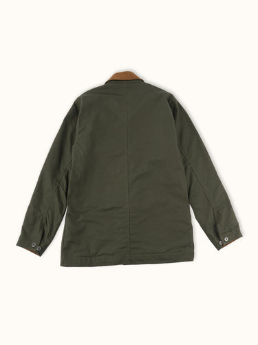 Campera confeccionada en canvas pesado de algodón, con cuello en corderoy a contratono. Acceso frontal con cierre de metal oculto y mosquetones de metal a la vista. Este detalle está inspirado en los uniformes de los bomberos, sirven principalmente para cerrar de forma segura y rápida las prendas, garantizando que no se abran durante la emergencia, además de resistir altas temperaturas. #color_verde