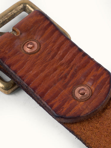 Cinturón modelo clásico confeccionado artesanalmente en cuero vacuno con terminación envejecida. Hebilla rectangular metálica grande en baño oro italiano y remaches baño cobre con refuerzo de cuero. Logo de marca grabado en bajo relieve. Forma parte de nuestra línea artesanal de accesorios de edición limitada, donde ningún producto es exactamente igual al otro. #color_marr-n