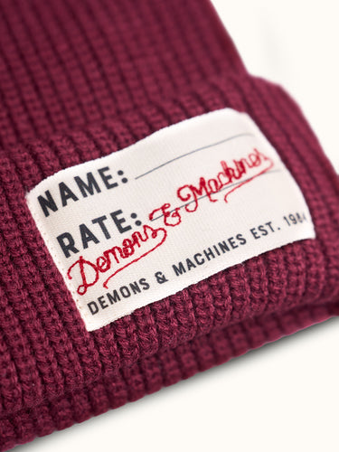 Gorro tejido Demons & Machines, estilo beanie, con textura de punto y ajuste cómodo para el invierno. #color_bordo