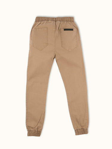 Pantalón Demons & Machines de corte jogger slim, confeccionado en gabardina elastizada. Bolsillos delanteros y bolsillo relojero bien jeaneros, cintura con elástico interno y cordón ajustable, bolsillos plaqué en trasero. #color_camel