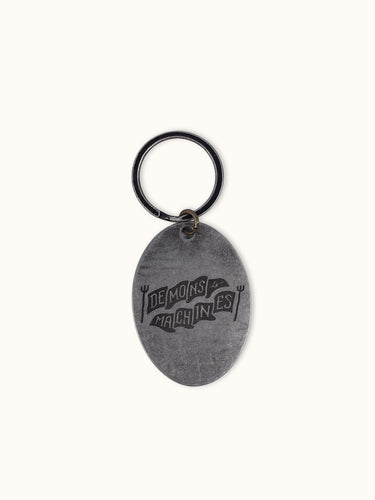 Llavero Sinclair de Demons & Machines con diseño metálico y detalles en relieve, ideal para llaves y accesorios.