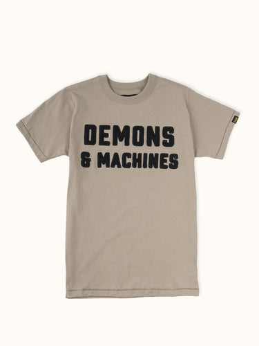 Remera Demons & Machines manga corta confeccionada en Jersey 16/1 de algodón peinado. Calce slim y cuello terminado en collareta con complemento ribb. Terminaciones de mangas y ruedo en dobladillo con costura india. Bordado marcaría al frente, con letras aplicadas en paño y pespuntes al tono. Suavizado sobre prenda terminada. #color_khaki