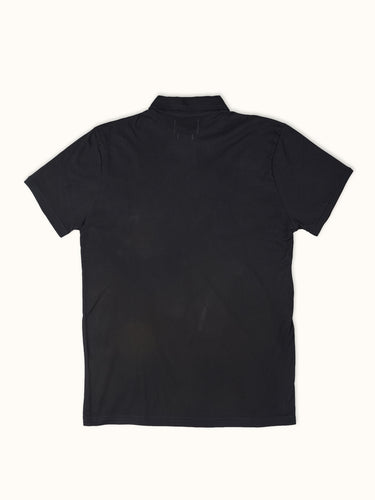Remera polo de manga corta Demons & Machines, 100% algodón premium, con diseño clásico, bordado en el pecho y cuello abotonado. #color_negro