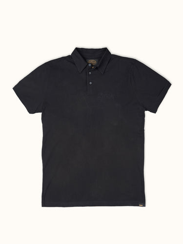 Remera polo de manga corta Demons & Machines, 100% algodón premium, con diseño clásico, bordado en el pecho y cuello abotonado. #color_negro