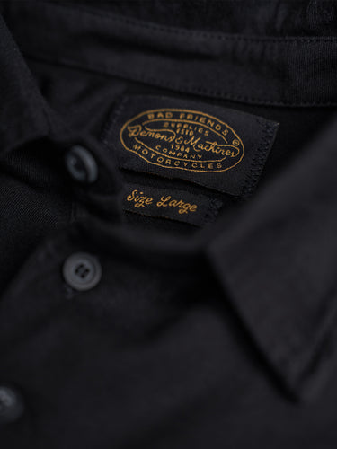Remera polo de manga corta Demons & Machines, 100% algodón premium, con diseño clásico, bordado en el pecho y cuello abotonado. #color_negro