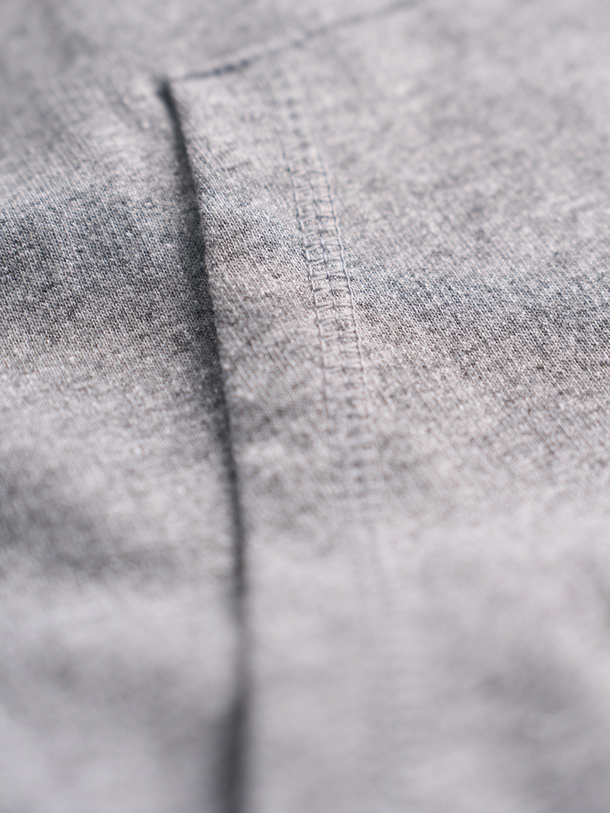 Detalle de la costura del bolsillo canguro sobre el tejido melange del Training Hood Vest gris