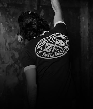 Modelo usando remera gráfica estilo vintage con estampa trasera “Speed Engineering” en entorno industrial desgastado — FALL/WINTER 2026 by DEMONS & MACHINES