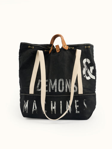 Bolso Militar negro de frente con estampa DEMONS & MACHINES, manijas de cuero y asas de cinta cruda #color_negro