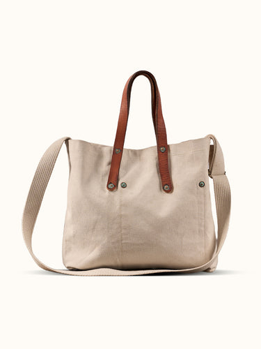Bolso Demons & Machines estilo tote confeccionado artesanalmente en lona pesada de algodón, con manija en cuero vacuno 100% y correa reforzada de algodón regulable. Herrajes metálicos en baño cobre empavonado oxidados artesanalmente. Cuenta con dos bolsillos internos. Logo de marca estampado en serigrafía con efecto gastado y roto.