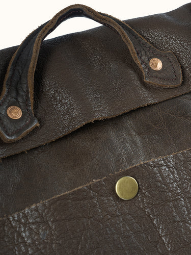 Detalle de la manija de cuero con remaches de cobre y el broche de la tapa del Bolso Messenger marrón #color_marron