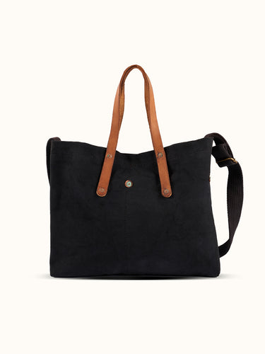 Bolso Demons & Machines estilo tote confeccionado artesanalmente en lona pesada de algodón, con manija en cuero vacuno 100% y correa reforzada de algodón regulable. Herrajes metálicos en baño cobre empavonado oxidados artesanalmente. Cuenta con dos bolsillos internos. Logo de marca estampado en serigrafía con efecto gastado y roto. #color_negro