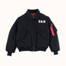 Campera Demons & Machines reversible estilo aviadora. Este estilo remite al modelo de camperas ALPHA, icónicas de la Fuerza Aérea por su diseño funcional para pilotos, caracterizadas por materiales resistentes, puños tejidos, bolsillos utilitarios y reversibilidad naranja para visibilidad en emergencias.