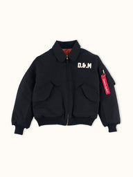 Campera Demons & Machines reversible estilo aviadora. Este estilo remite al modelo de camperas ALPHA, icónicas de la Fuerza Aérea por su diseño funcional para pilotos, caracterizadas por materiales resistentes, puños tejidos, bolsillos utilitarios y reversibilidad naranja para visibilidad en emergencias.