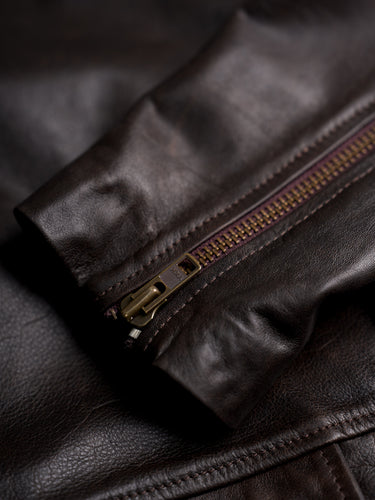 Campera de Demons & Machines confeccionada en cuero vacuno gastado. Calce regular, cuello alto con presilla de ajuste mediante hebilla metálica, acceso con botones pasta negros y ojales sastreros. El corte y confección de cada una de nuestras camperas de cuero se lleva a cabo de manera artesanal y personalizada. 