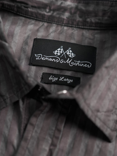Camisa Demons & Machines confeccionada en poplin de algodón escocés con proceso de engrasado sobre prenda terminada. Broches perla negros en cartera y cuello. Bolsillos plaqué con tapa al frente.