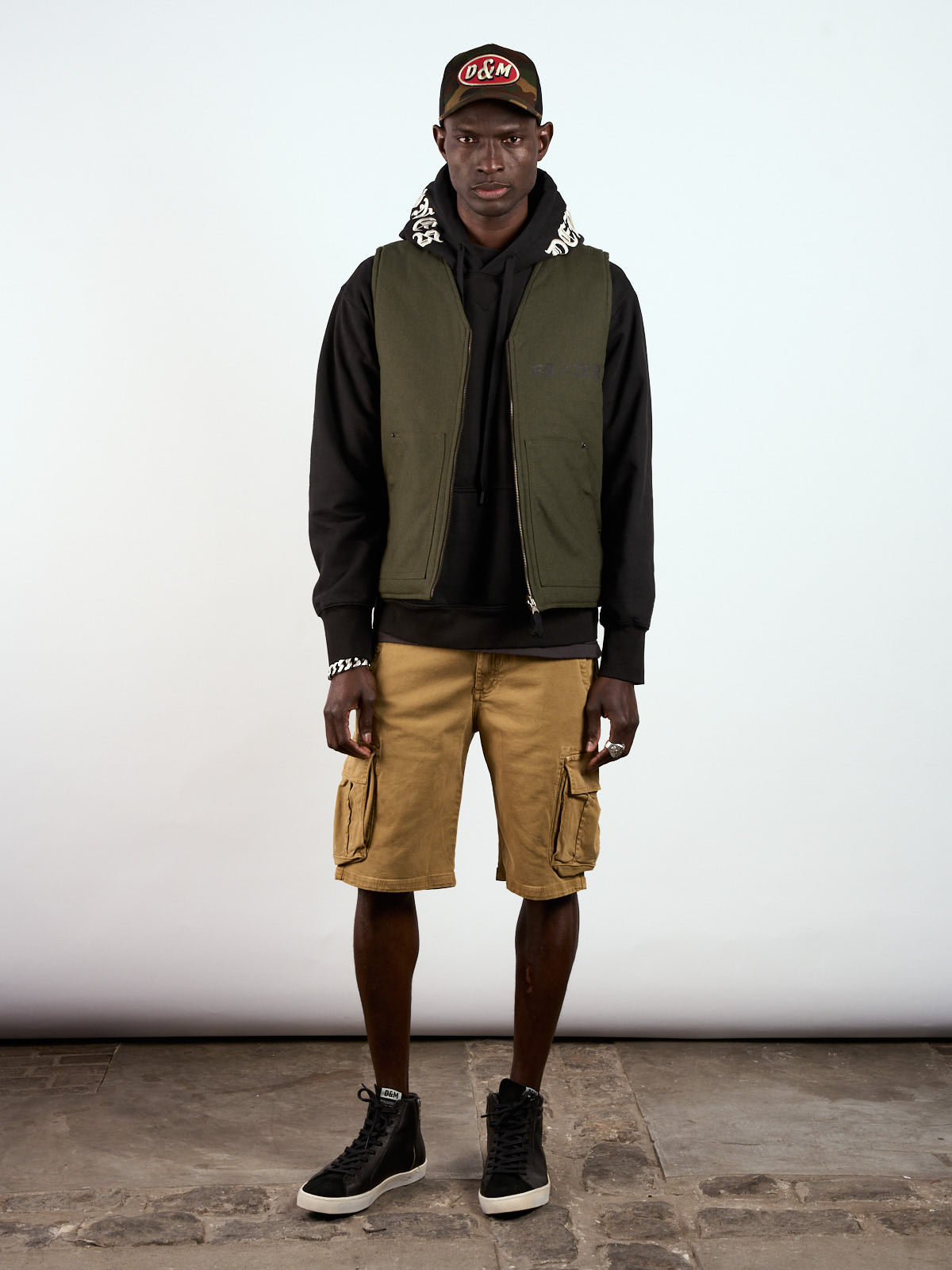 Chaleco State Reversible puesto sobre hoodie negro, cuerpo entero con bermuda camel y zapatillas #color_negro