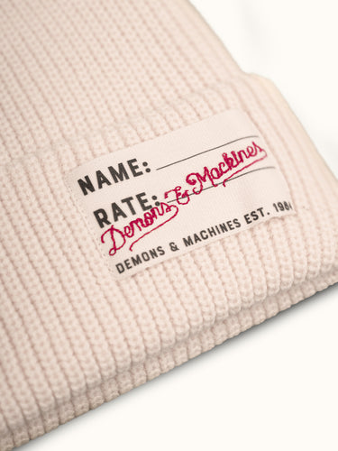 Gorro tejido Demons & Machines, estilo beanie, con textura de punto y ajuste cómodo para el invierno. #color_offwhite