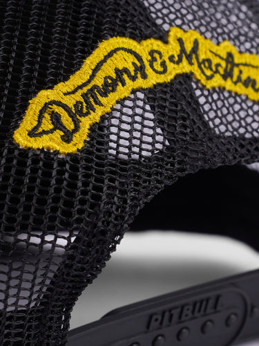 Gorra Podium de Demons & Machines con diseño camuflaje, vista frontal con visera y detalles en el estilo de gorra deportiva.