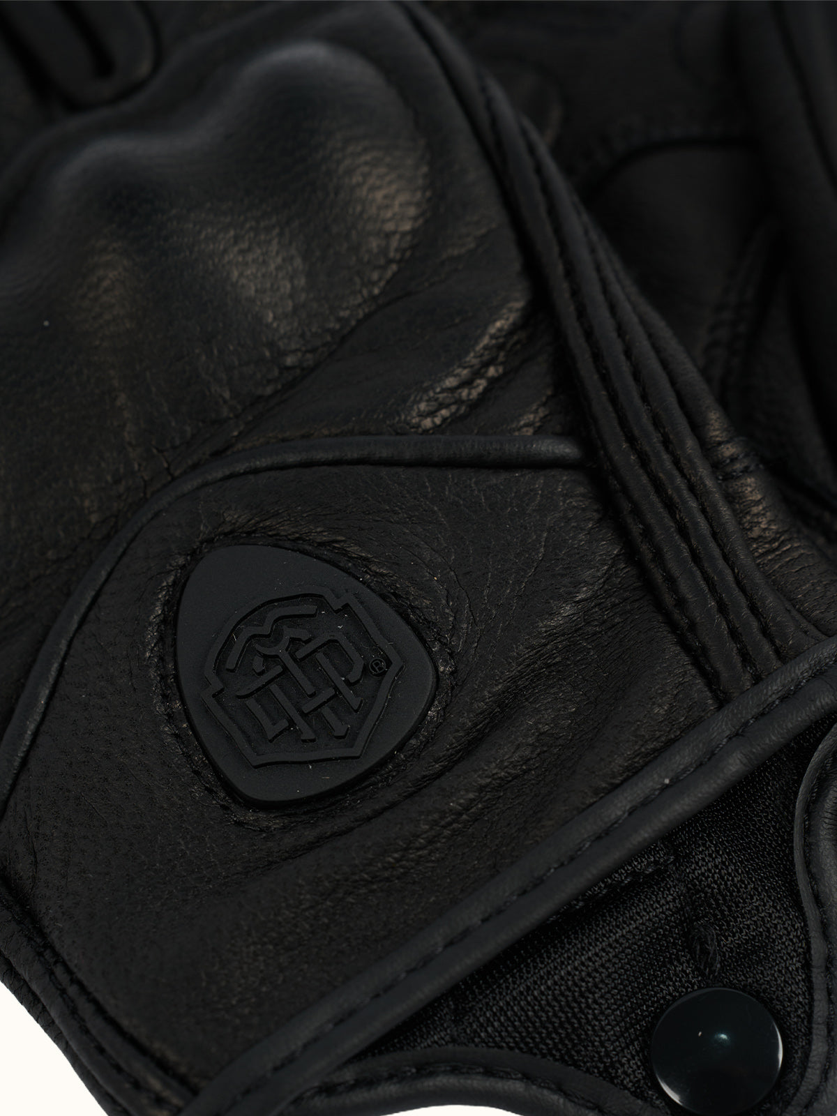 Detalle del dorso de los Guantes Redwood: protector de nudillos acolchado y escudo con logo en relieve