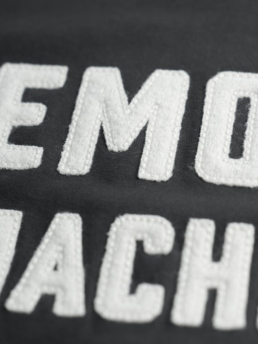 Remera Demons & Machines manga corta confeccionada en Jersey 16/1 de algodón peinado. Calce slim y cuello terminado en collareta con complemento ribb. Terminaciones de mangas y ruedo en dobladillo con costura india. Bordado marcaría al frente, con letras aplicadas en paño y pespuntes al tono. Suavizado sobre prenda terminada. #color_negro