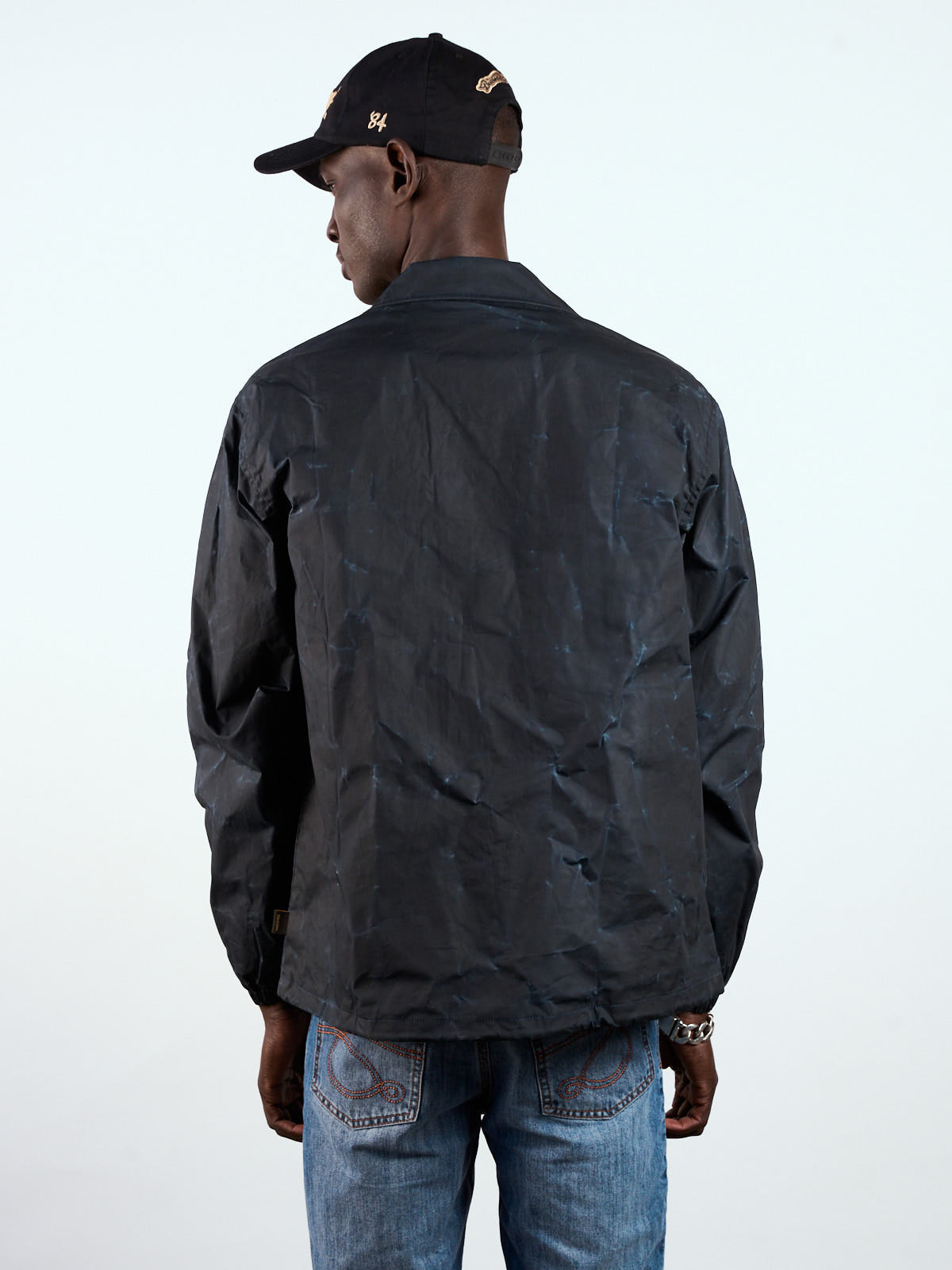 Rompeviento Nashville Wax azul puesto, vista de espalda con gorra negra y jean claro #color_azul