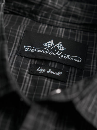 Camisa de Demons & Machines confeccionada en poplin de algodón escocés con proceso de engrasado sobre prenda terminada. Broches perla negros en cartera y cuello. Bolsillos plaqué con tapa al frente.
