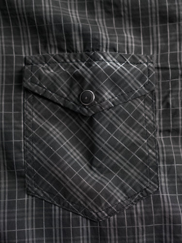 Camisa de Demons & Machines confeccionada en poplin de algodón escocés con proceso de engrasado sobre prenda terminada. Broches perla negros en cartera y cuello. Bolsillos plaqué con tapa al frente.