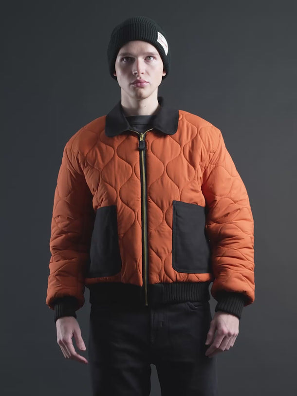 Campera Demons & Machines reversible estilo aviadora. Este estilo remite al modelo de camperas ALPHA, icónicas de la Fuerza Aérea por su diseño funcional para pilotos, caracterizadas por materiales resistentes, puños tejidos, bolsillos utilitarios y reversibilidad naranja para visibilidad en emergencias.