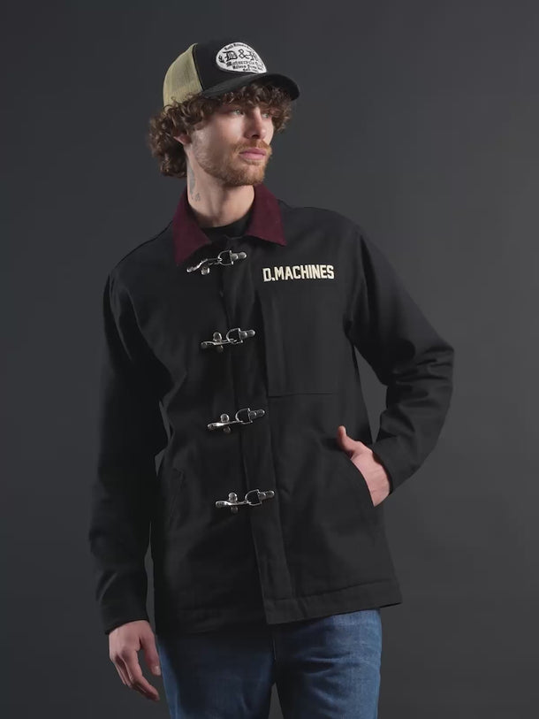 Campera confeccionada en canvas pesado de algodón, con cuello en corderoy a contratono.  Acceso frontal con cierre de metal oculto y mosquetones de metal a la vista. Este detalle está inspirado en los uniformes de los bomberos, sirven principalmente para cerrar de forma segura y rápida las prendas, garantizando que no se abran durante la emergencia, además de resistir altas temperaturas. #color_negro